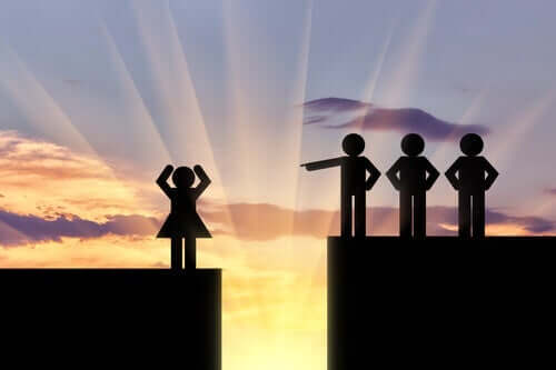 Mænd peger fingre af kvinde på den anden side af afgrund, som symbol for sexisme og kønsdebatten