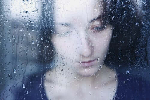 kvinde bag regnfyldt vindue