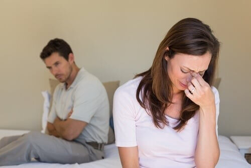 Grædende kvinde med mand i baggrund oplever kedsomhed i et forhold