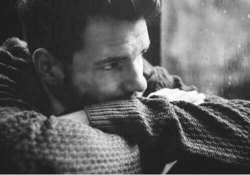 trist mand, der kigger ud af vindue