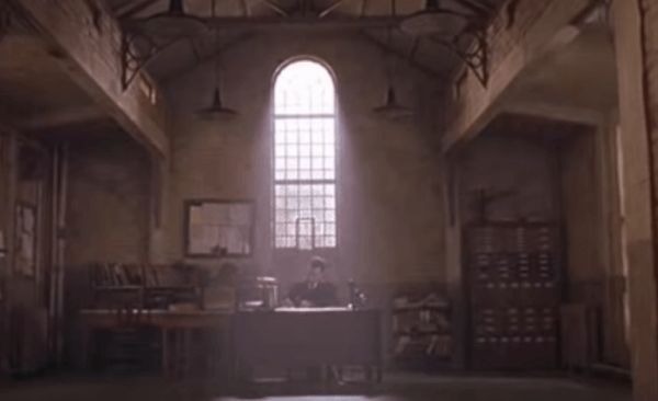 En mand, der sidder ved et skrivebord i et mørkt rum i et fængsel