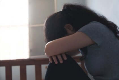 kvinde med armene over sine knæ oplever negativ selvopfattelse under en depression