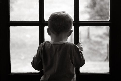 Dreng kigger ud af vindue og symboliserer depression hos børn