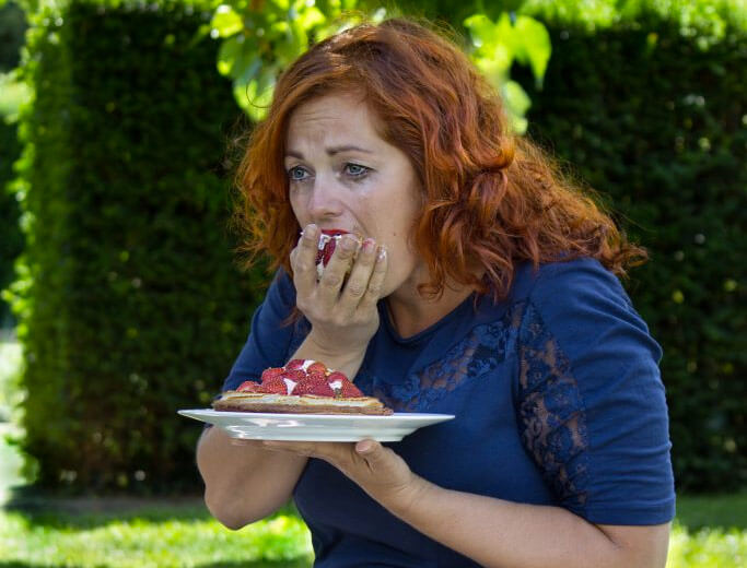 Grædende kvinde spiser en hel jordbærtærte