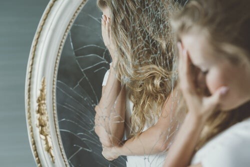 Nedtrykt pige står foran knust spejl 