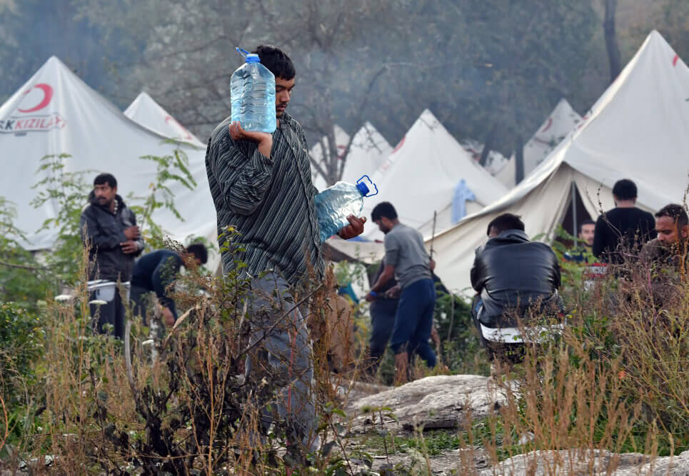 Mand i lejr går med vand som eksempel på støtte efter katastrofer