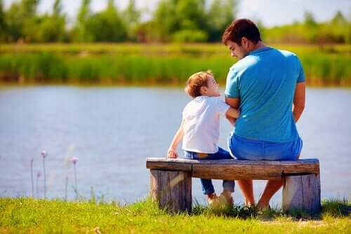 Far og søn ved sø viser, hvordan man kan sige undskyld til børn