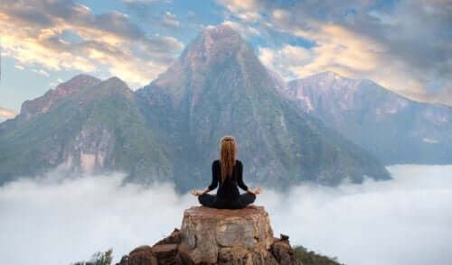 Kvinde på bjergtop udøver meditation som et middel mod mental træthed.