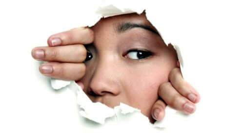 Kvinde bag lille hul i væg prøver at overvinde generthed