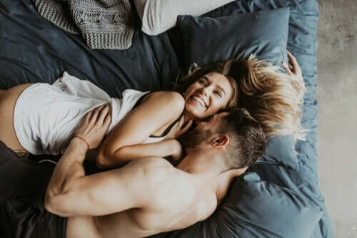 Grinende par i seng illustrerer et lykkeligt parforhold