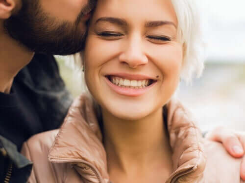 Mand kysser smilende kvinde i håret