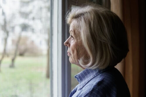 Ældre kvinde kigger ud af vinduet 