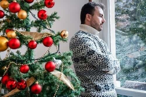 Fortvivlet mand ved juletræ har problemer med at være selvsikker i familien i juledagene