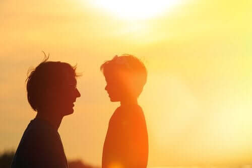 Silhuetter af mand, der taler med søn foran solen