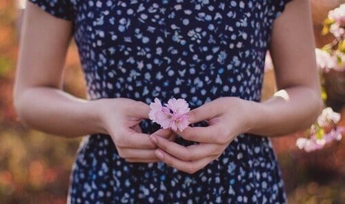 Kvinde står med blomst i hånden