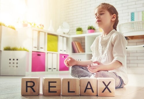 Pige mediterer ved siden af træklodser, der danner ordet "relax"