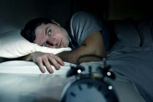 mand ligger søvnløs i sengen som resultat af at gå i seng med vrede