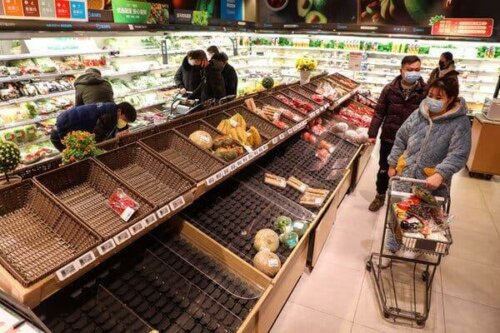 Folk handler i supermarked med tomme hylder grundet coronavirus hamstring