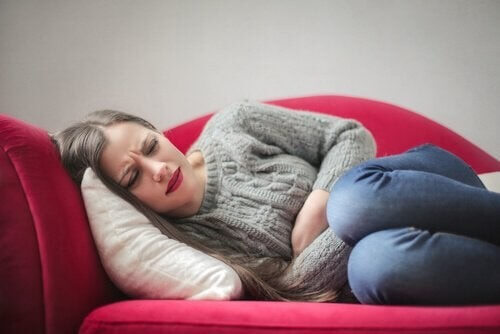 Kvinde ligger på sofaen med kraftige smerter 