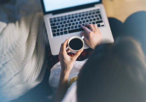 Person, der arbejder på computer og drikker kaffe