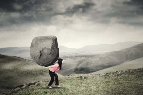 kvinde bærer meget stor sten på ryggen
