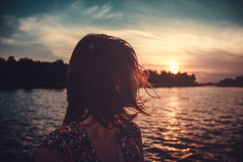 Kvinde ser ud over sø med sol