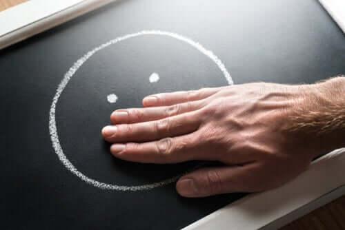 Person holder hånd over mund på smiley som symbol for brud på ytringsfrihed