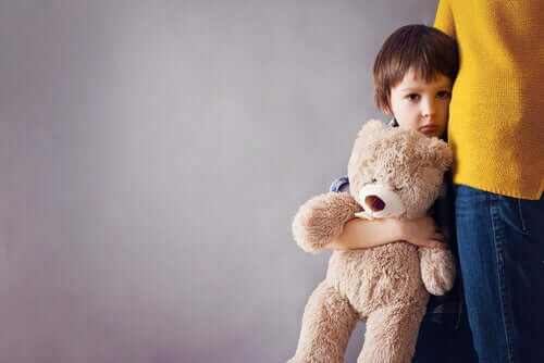 Barn med bamse i armene står tæt på voksen