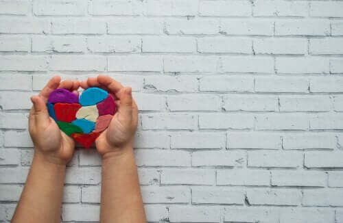 Børnehænder der holder et hjerte af modellervoks