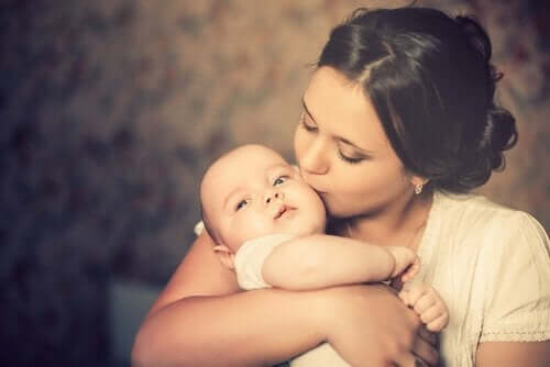 Mor, der kysser baby på kinden
