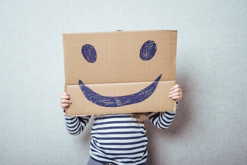 Følelsesmæssig uddannelse: Et barn bag et smiley papskilt
