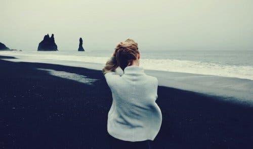 Kvinde, der sidder ved strand, tænker over, hvordan man reagerer på forskellige situationer