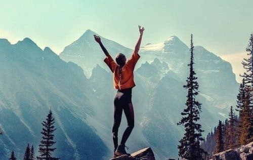 Kvinde, der står sejrende på bjerg