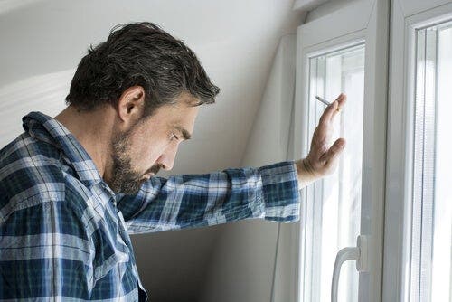 Mand, der står ved vindue og ryger