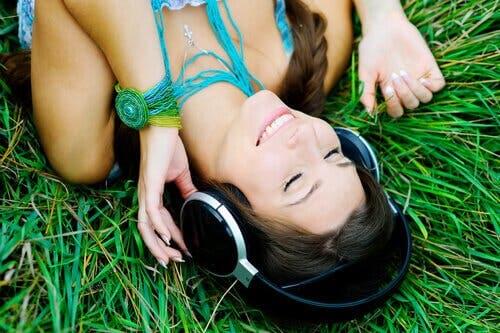 Glad kvinde på græs lytter til musik