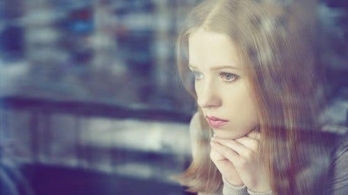 Kvinde, der kigger trist ud af vindue