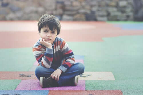 Trist dreng sidder på legeplads
