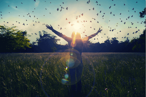 Kvinde med armene ud til siderne og fugle omkring sig