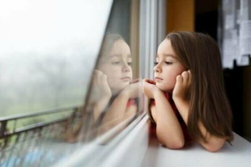 Pige kigger ud af vindue som symbol på børns frygt