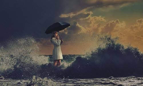 Kvinde, der står med en paraply i havet