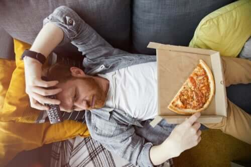 Mand ligger på sofa med pizza