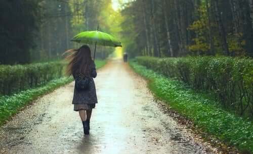 Kvinde, der går med paraply i regn