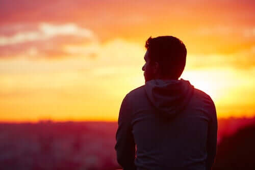 Mand står foran solnedgang