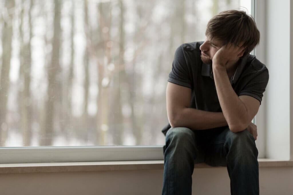 Trist mand, der kigger ud af vindue