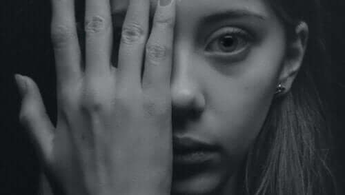 Ung kvinde, der holder sin hånd foran halvdelen af sit ansigt