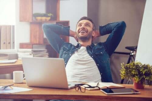 Smilende mand ved skrivevord besidder professionel selvbevidsthed