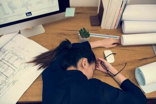 Kvinde, der ligger udmattet over skrivebord