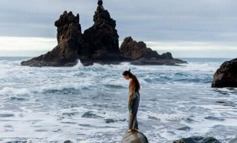 Kvinde, der står på sten ud mod havet