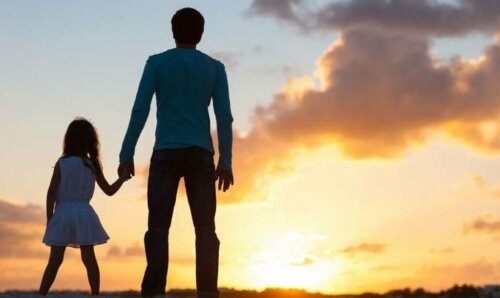 Far og datter hånd i hånd foran solnedgang