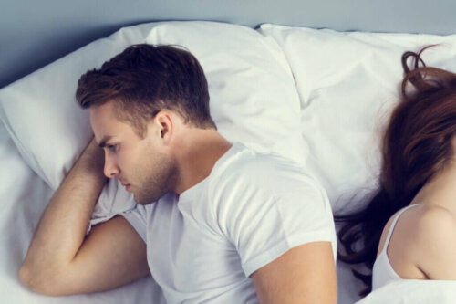 Mand og kvinde ligger med ryggen mod hinanden i en seng